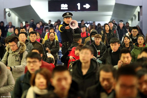 A policeman keeps order at Yuncheng North railway station in Chinas Shanxi Province today as travellers pack the space