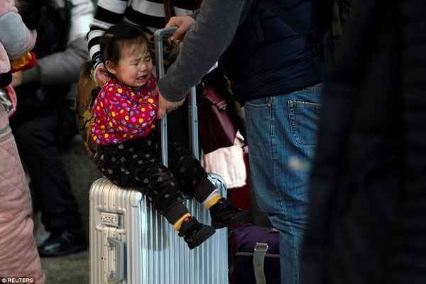 A child cries on a suitcase at Shanghais Hongqiao Railway Station as people pack the traffic hub on the first day of travel rush