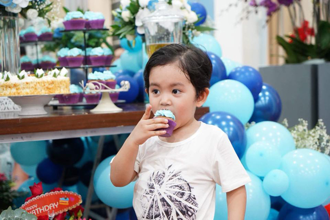Cậu nhóc 3 tuổi lém lỉnh ăn bánh mà không quan tâm đến mọi người xung quanh. 
